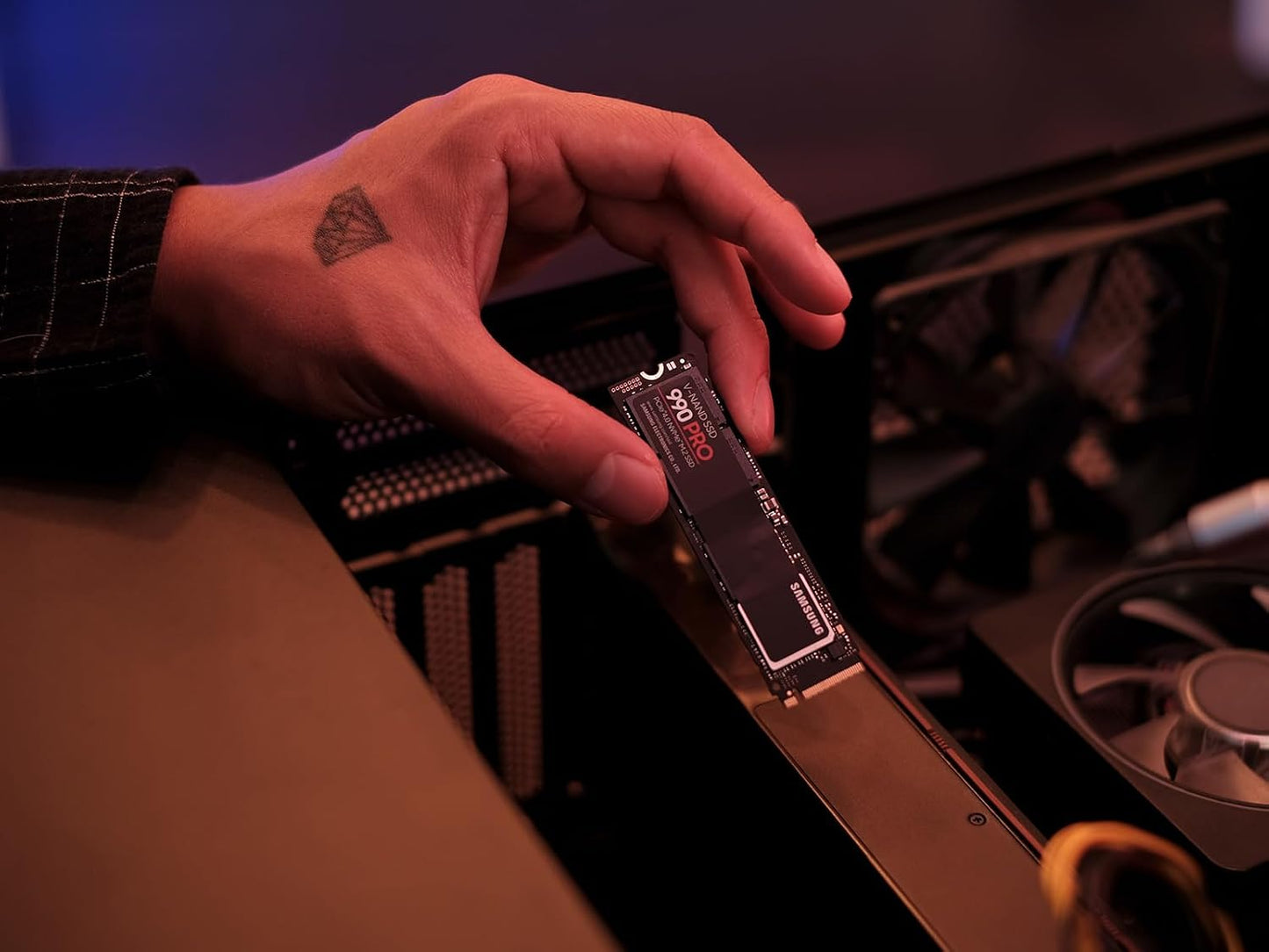 Samsung 990 PRO 2TB NVMe PCIe 4.0 SSD — held in hand beside an open PC