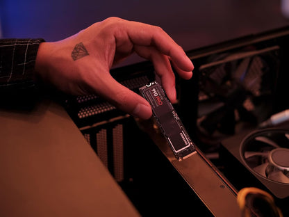 Samsung 990 PRO 2TB NVMe PCIe 4.0 SSD — held in hand beside an open PC