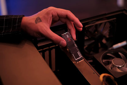 Samsung 990 PRO 1TB NVMe PCIe 4.0 SSD — held in hand beside an open PC