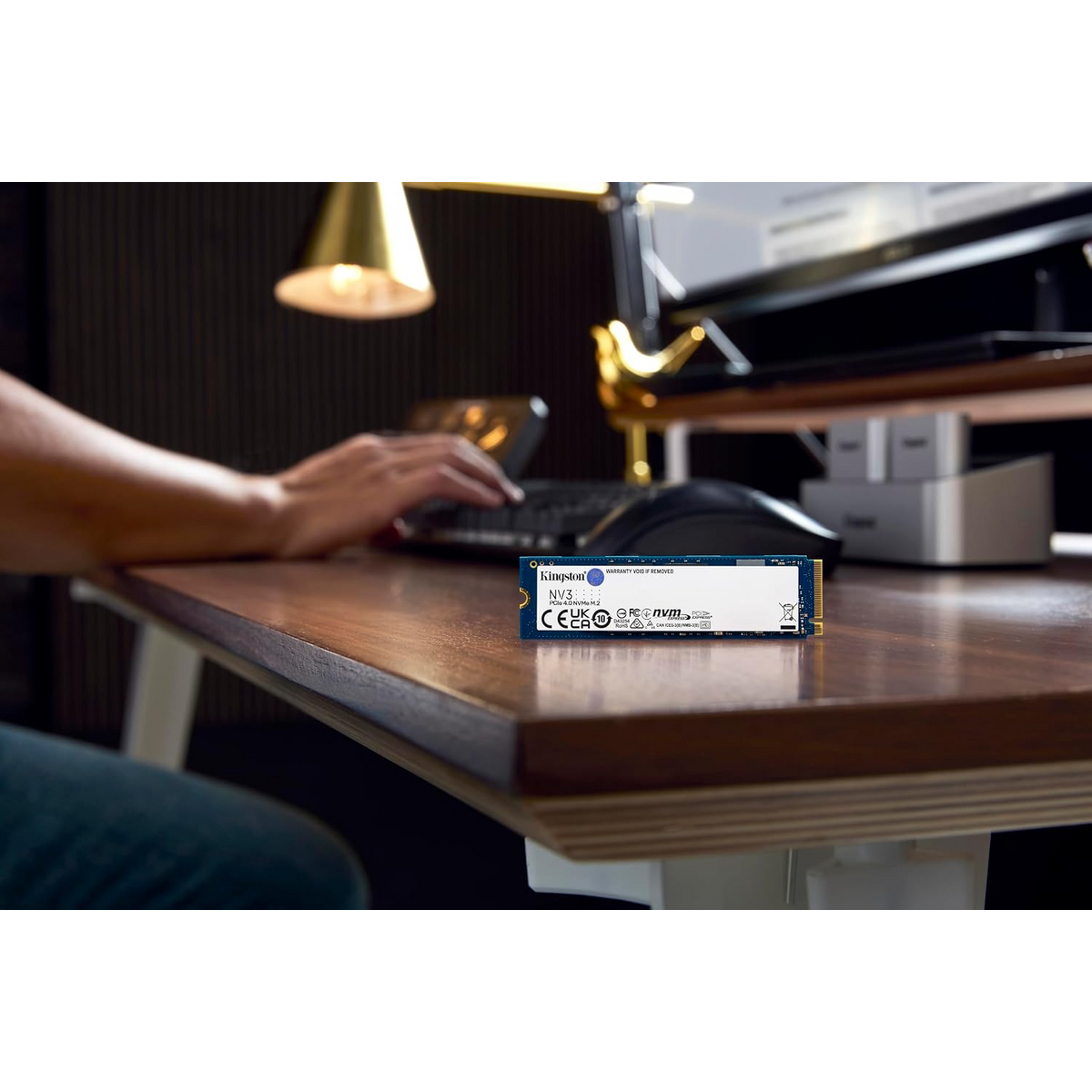 Kingston NV3 1TB PCIe 4.0 NVMe M.2 Internal SSD — on a desk beside a workstation