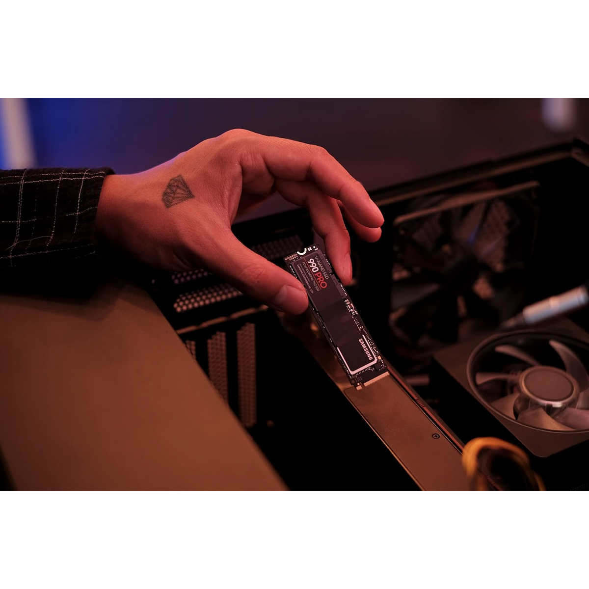 Samsung 990 PRO 1TB NVMe PCIe 4.0 SSD — held in hand beside an open PC