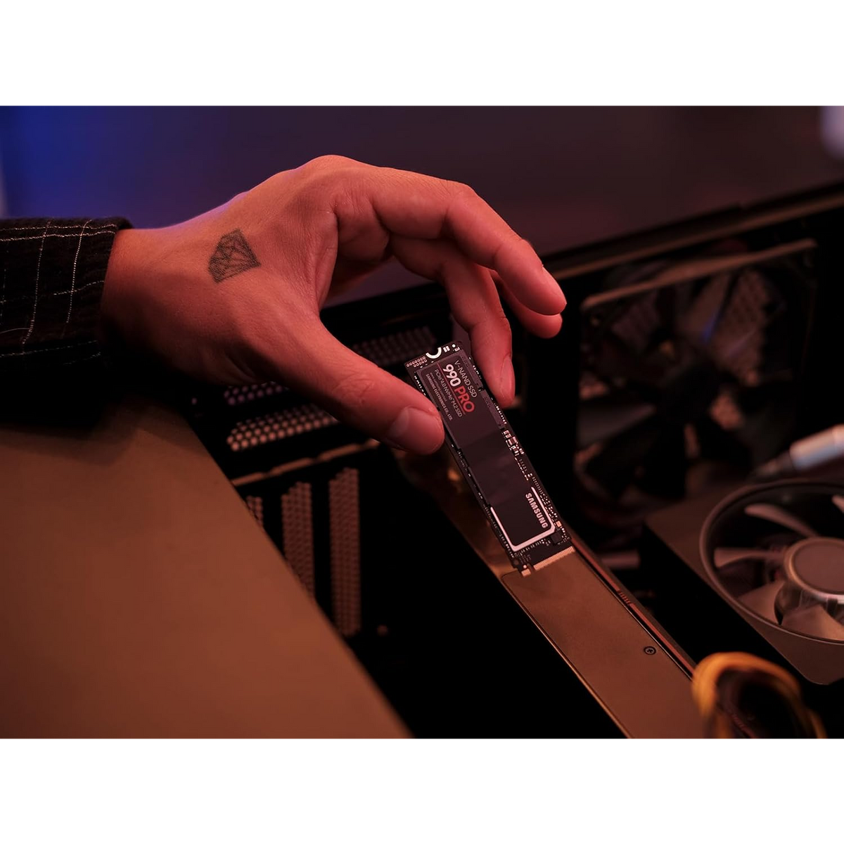 Samsung 990 PRO 2TB NVMe PCIe 4.0 SSD — held in hand beside an open PC