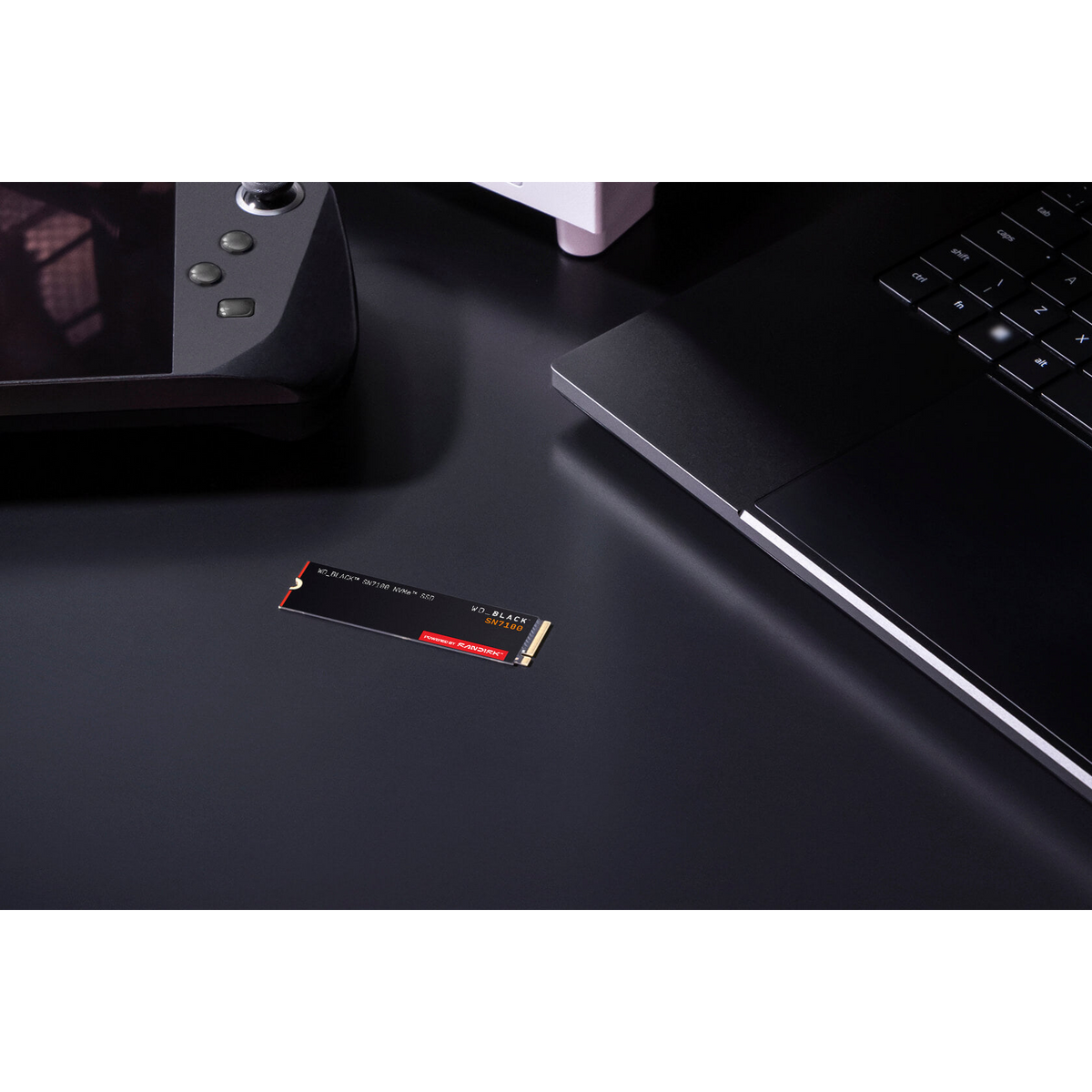 WD_BLACK SN7100 2TB NVMe SSD — shown on a desk beside a handheld console