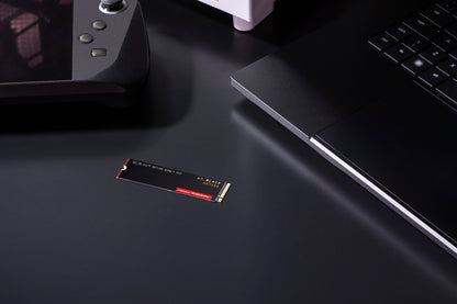 WD_BLACK SN7100 1TB NVMe SSD — shown on a desk beside a handheld console